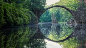 im kreisförmigen bogen wölbt sich das mondtor als brücke über das wasser im keltenwald bei kromlau